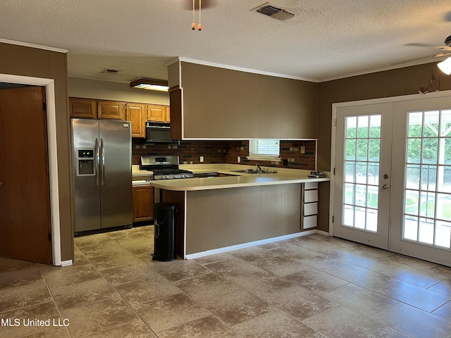 2 Concord Pl, Gulfport, MS 39507 - kitchen with stainless steel appliances, a peninsula, a textured ceiling, brown cabinetry, and light countertops
