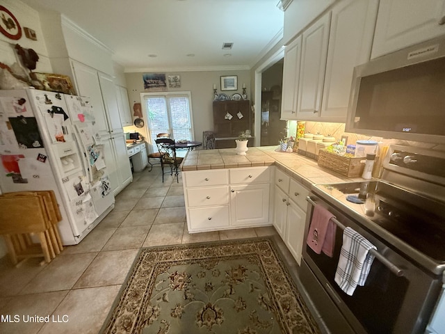 771 Versailles Dr, Ridgeland, MS 39157 - kitchen featuring appliances with stainless steel finishes, a peninsula, white cabinetry, ornamental molding, and tile countertops