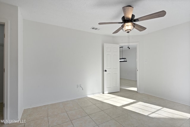 tiled spare room with a textured ceiling and ceiling fan