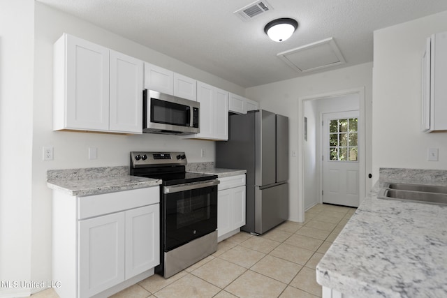 kitchen featuring a textured ceiling, white cabinets, and stainless steel appliances