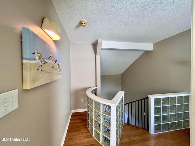 8102 Fairway Villa Dr, Gautier, MS 39553 - corridor featuring wood finished floors, a textured ceiling, lofted ceiling, and an upstairs landing
