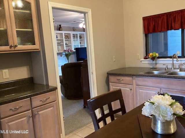 8102 Fairway Villa Dr, Gautier, MS 39553 - kitchen with light colored carpet, dark countertops, light tile patterned floors, glass insert cabinets, and crown molding