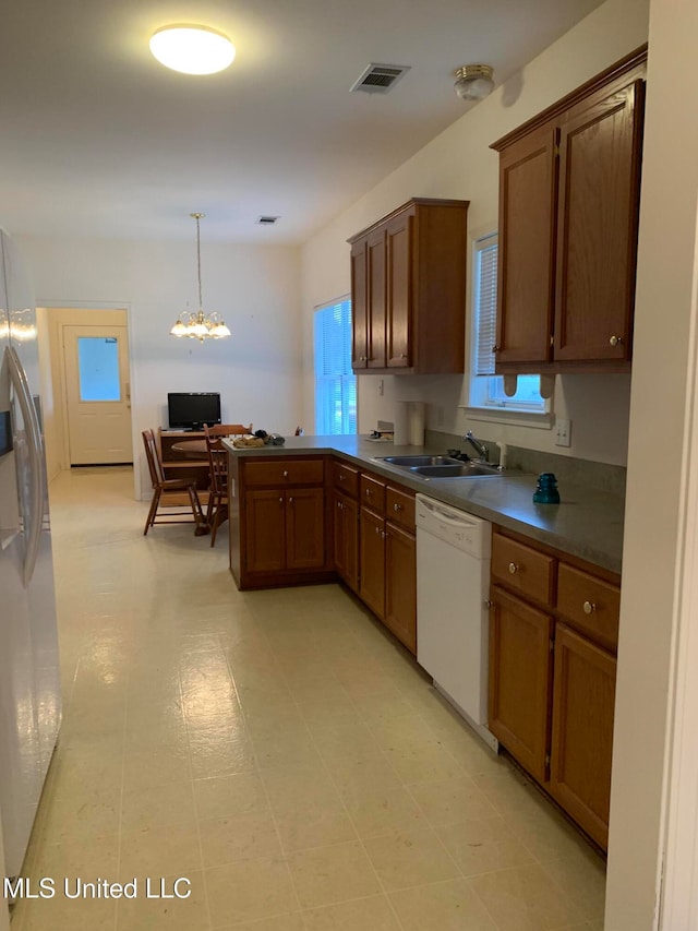 kitchen featuring pendant lighting, sink, dishwasher, stainless steel refrigerator with ice dispenser, and kitchen peninsula