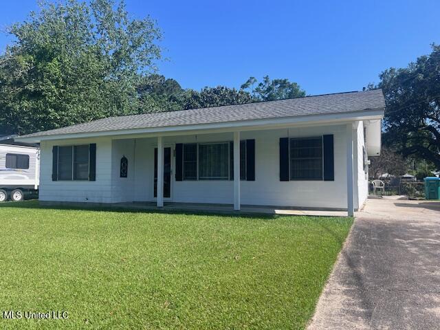 ranch-style home with roof with shingles, covered porch, and a front yard