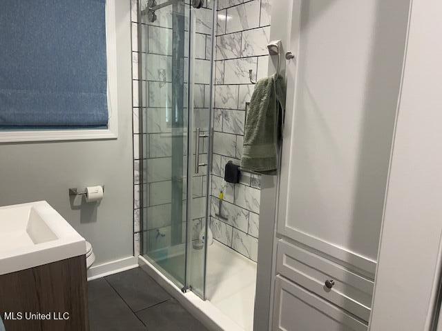 full bath with baseboards, a shower stall, tile patterned floors, and vanity