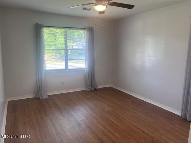 empty room with baseboards, ceiling fan, visible vents, and wood finished floors