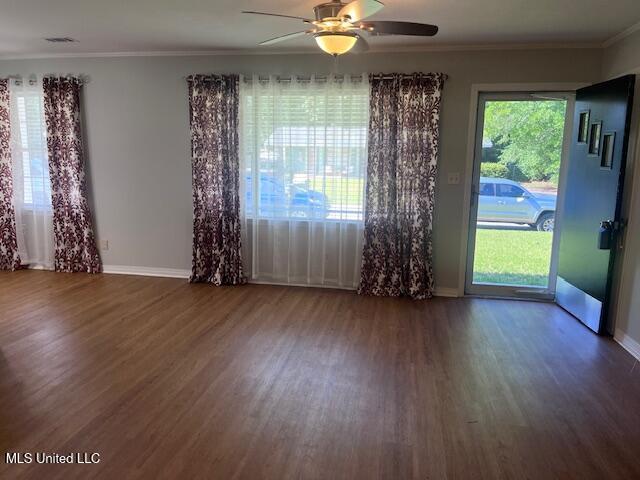 spare room with baseboards, a ceiling fan, wood finished floors, and ornamental molding