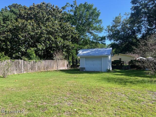view of yard with an outdoor structure, fence, and a detached garage