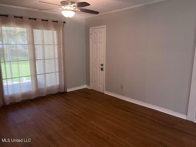 unfurnished room with baseboards, ornamental molding, ceiling fan, and dark wood-style floors