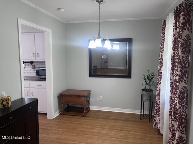 dining room with baseboards, crown molding, wood finished floors, and a notable chandelier