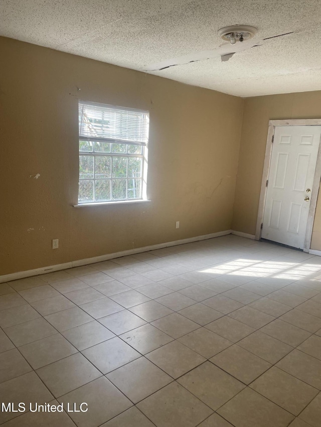 tiled spare room featuring baseboards and a textured ceiling