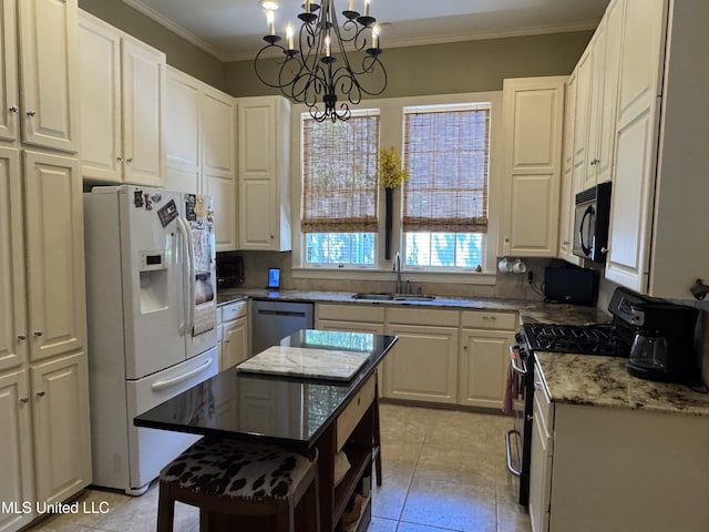 kitchen with white cabinetry, a chandelier, light stone counters, a sink, and appliances with stainless steel finishes