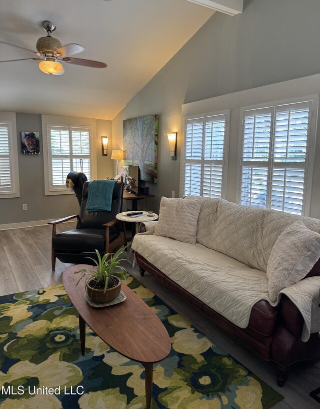 living area featuring baseboards, a ceiling fan, wood finished floors, and vaulted ceiling