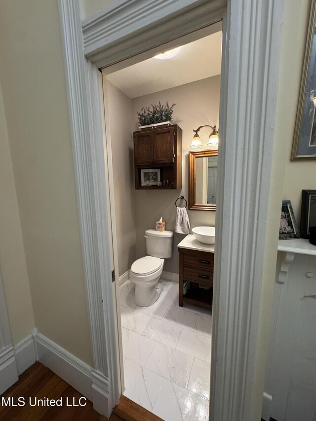 bathroom featuring baseboards, toilet, and vanity