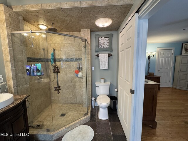 full bathroom with toilet, a stall shower, wood finished floors, and vanity