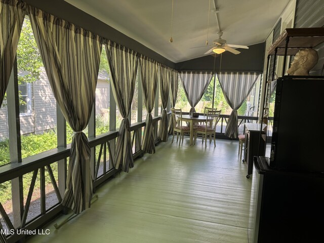sunroom with vaulted ceiling, a ceiling fan, outdoor dining area, and wood finished floors