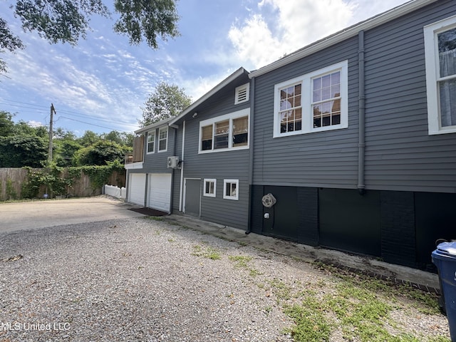 view of side of property with fence, driveway, and a garage