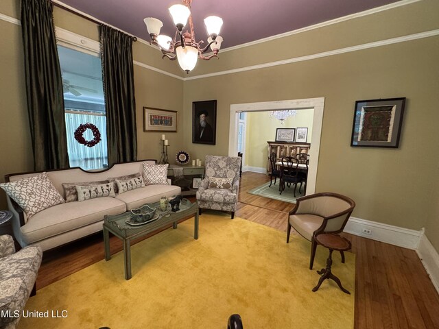 living room with baseboards, ornamental molding, wood finished floors, and a chandelier