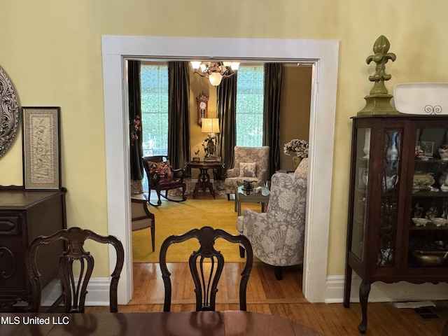 living area with baseboards, wood finished floors, and a notable chandelier