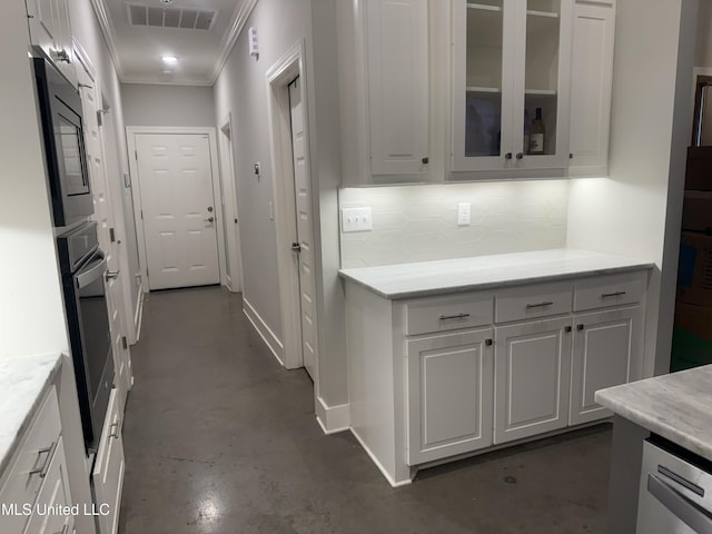 kitchen featuring black microwave, white cabinetry, oven, backsplash, and crown molding