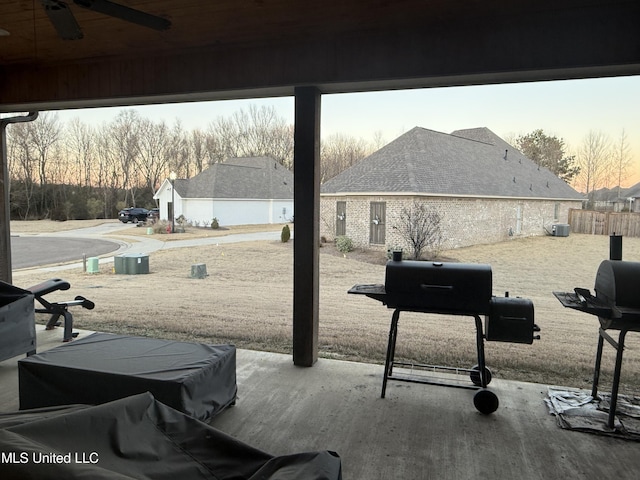 patio terrace at dusk featuring area for grilling and ceiling fan