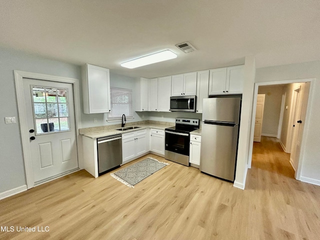 kitchen featuring white cabinetry, sink, light hardwood / wood-style flooring, and appliances with stainless steel finishes