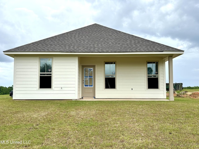 back of property featuring a shingled roof and a yard