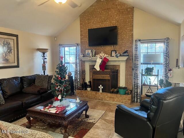 living room with ceiling fan, lofted ceiling, and a brick fireplace