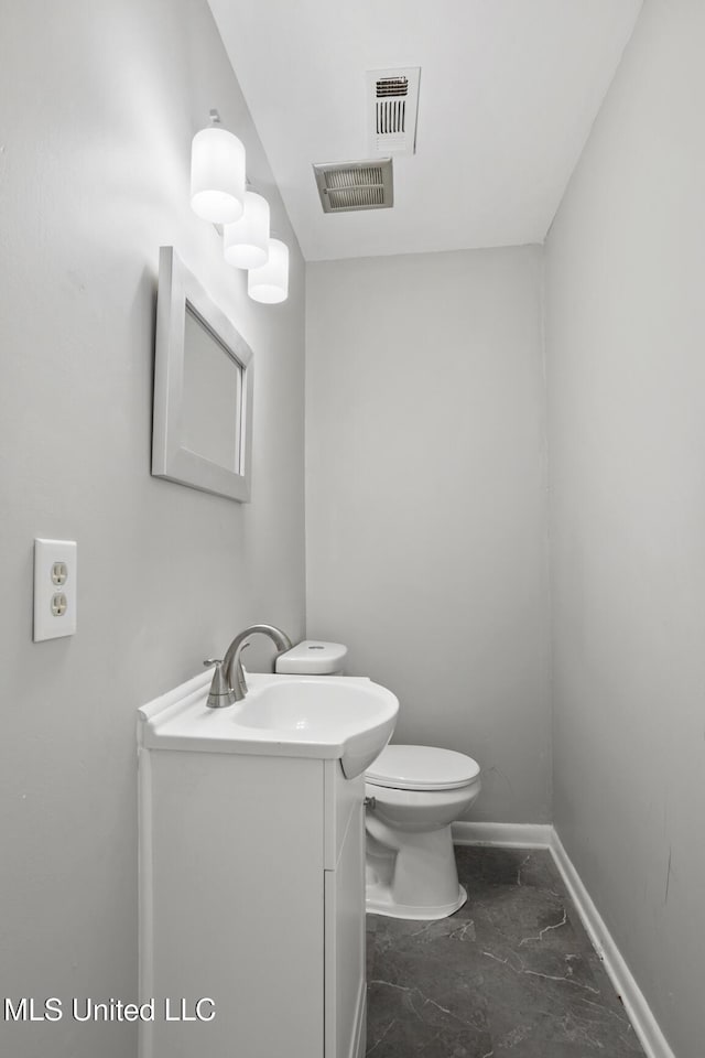 half bath with visible vents, baseboards, toilet, and vanity