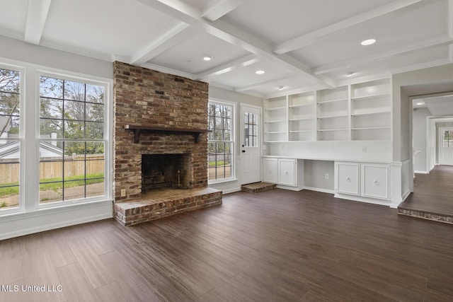 unfurnished living room featuring beam ceiling, a brick fireplace, and dark wood-style floors