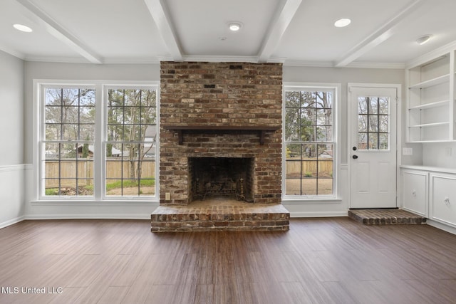 unfurnished living room featuring a wealth of natural light, beamed ceiling, a brick fireplace, and dark wood-style floors