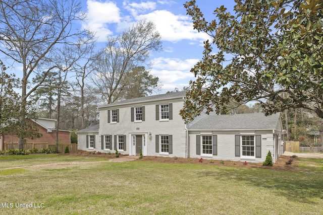 colonial home with a front yard, fence, and brick siding