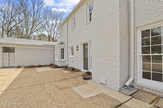 view of property exterior featuring a patio and brick siding