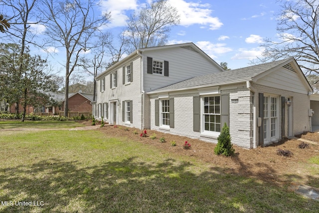 view of property exterior featuring brick siding, a lawn, and a shingled roof