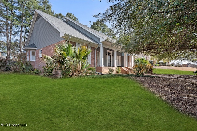 view of front of property featuring brick siding, covered porch, and a front yard