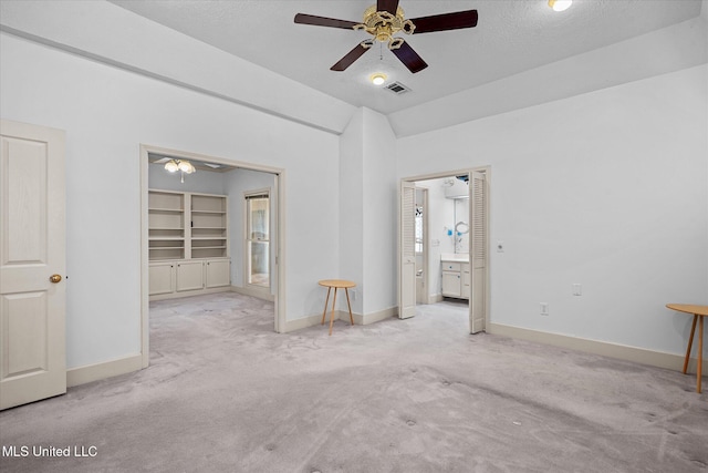 empty room with carpet flooring, baseboards, visible vents, and vaulted ceiling