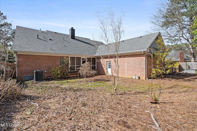 rear view of property featuring brick siding, a shingled roof, fence, central AC unit, and a chimney