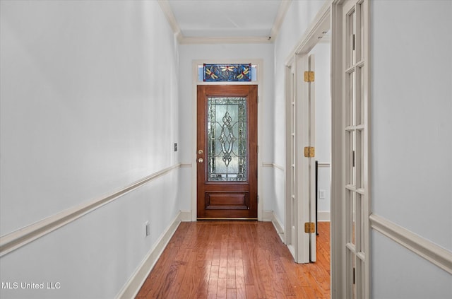 doorway featuring hardwood / wood-style flooring, baseboards, and ornamental molding