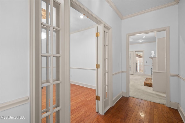 corridor featuring baseboards, hardwood / wood-style floors, and crown molding