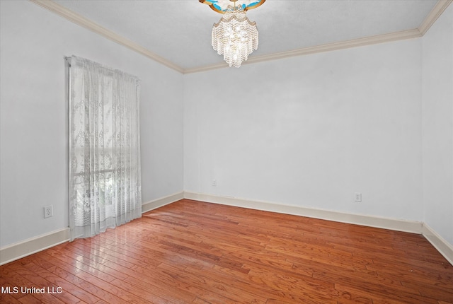 spare room featuring baseboards, crown molding, an inviting chandelier, and hardwood / wood-style floors