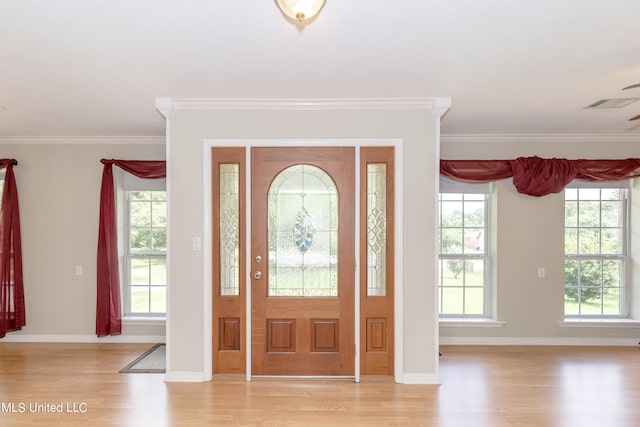 entrance foyer featuring light hardwood / wood-style flooring, ornamental molding, and a wealth of natural light