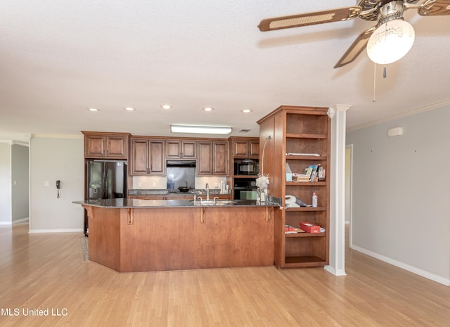 kitchen with light hardwood / wood-style flooring, black appliances, a breakfast bar, and crown molding