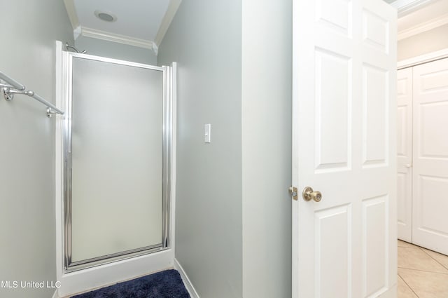 bathroom featuring a shower with door, crown molding, and tile patterned floors