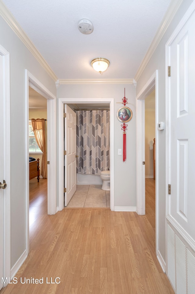 hallway with crown molding and light hardwood / wood-style floors