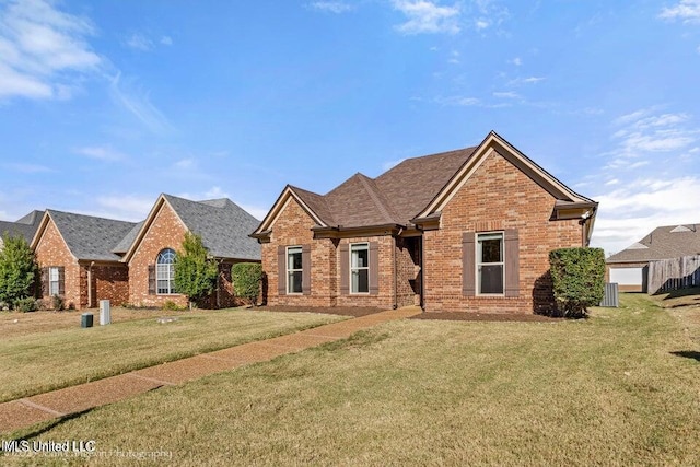 view of front of property with roof with shingles, a front lawn, and brick siding