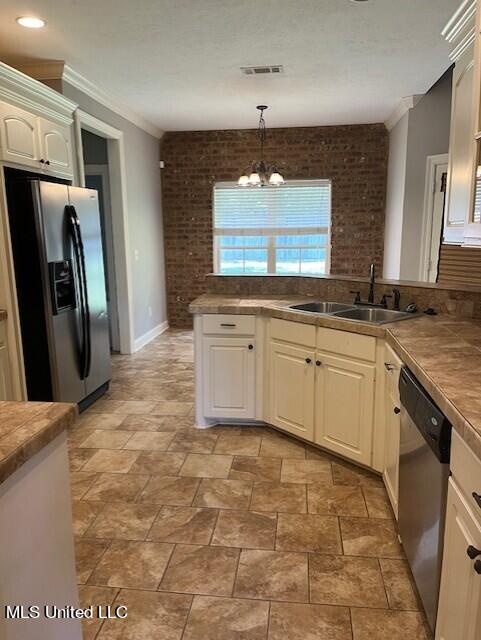 kitchen featuring appliances with stainless steel finishes, sink, hanging light fixtures, white cabinetry, and a notable chandelier