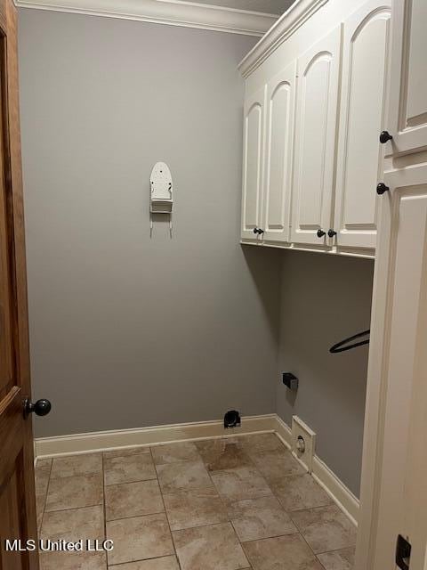 clothes washing area featuring ornamental molding and cabinets