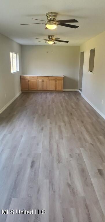 unfurnished room featuring baseboards, light wood-type flooring, and ceiling fan