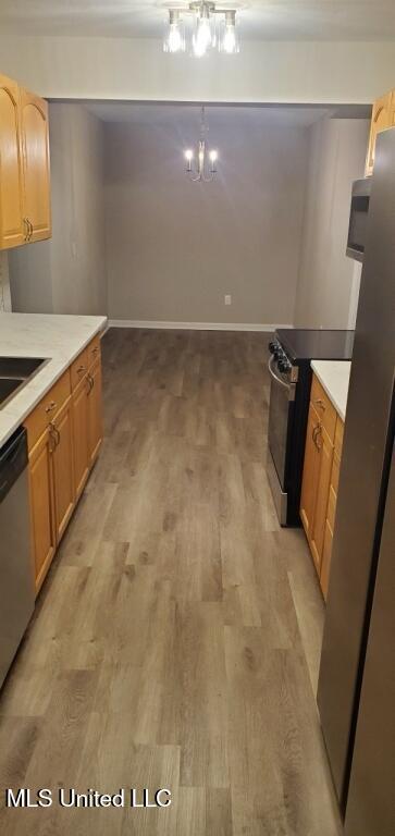 kitchen featuring light wood finished floors, appliances with stainless steel finishes, light countertops, and a sink