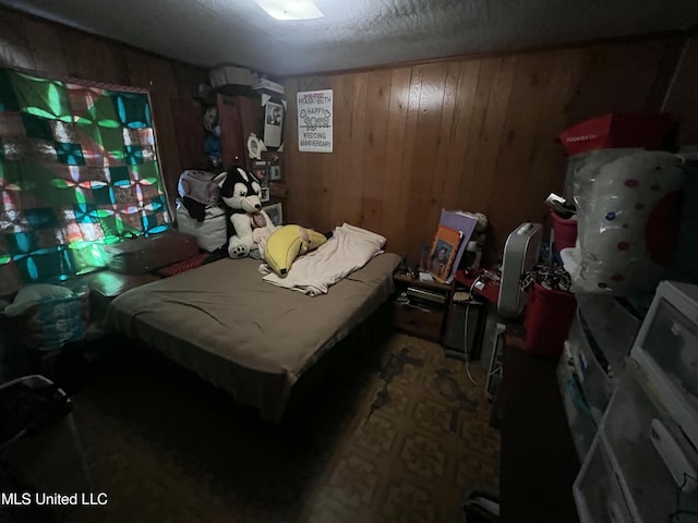 bedroom featuring wood walls and a textured ceiling